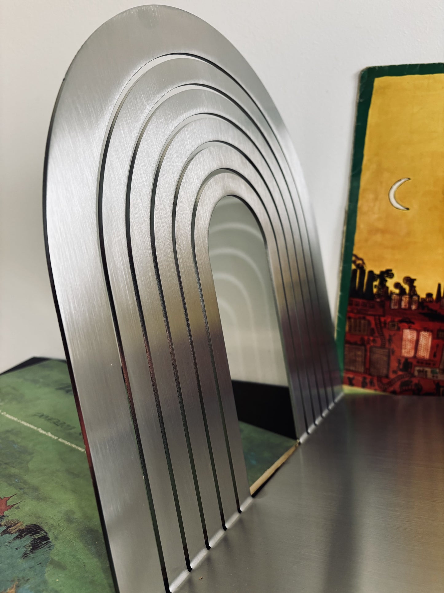 Metallic arch-shaped object on a reflective surface with a blurred background