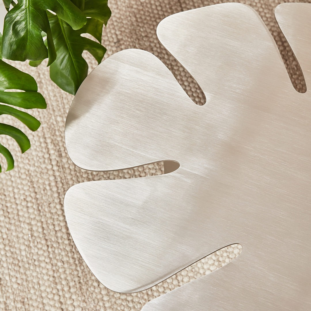 Organic curves of a Monstera-inspired brushed steel coffee table.