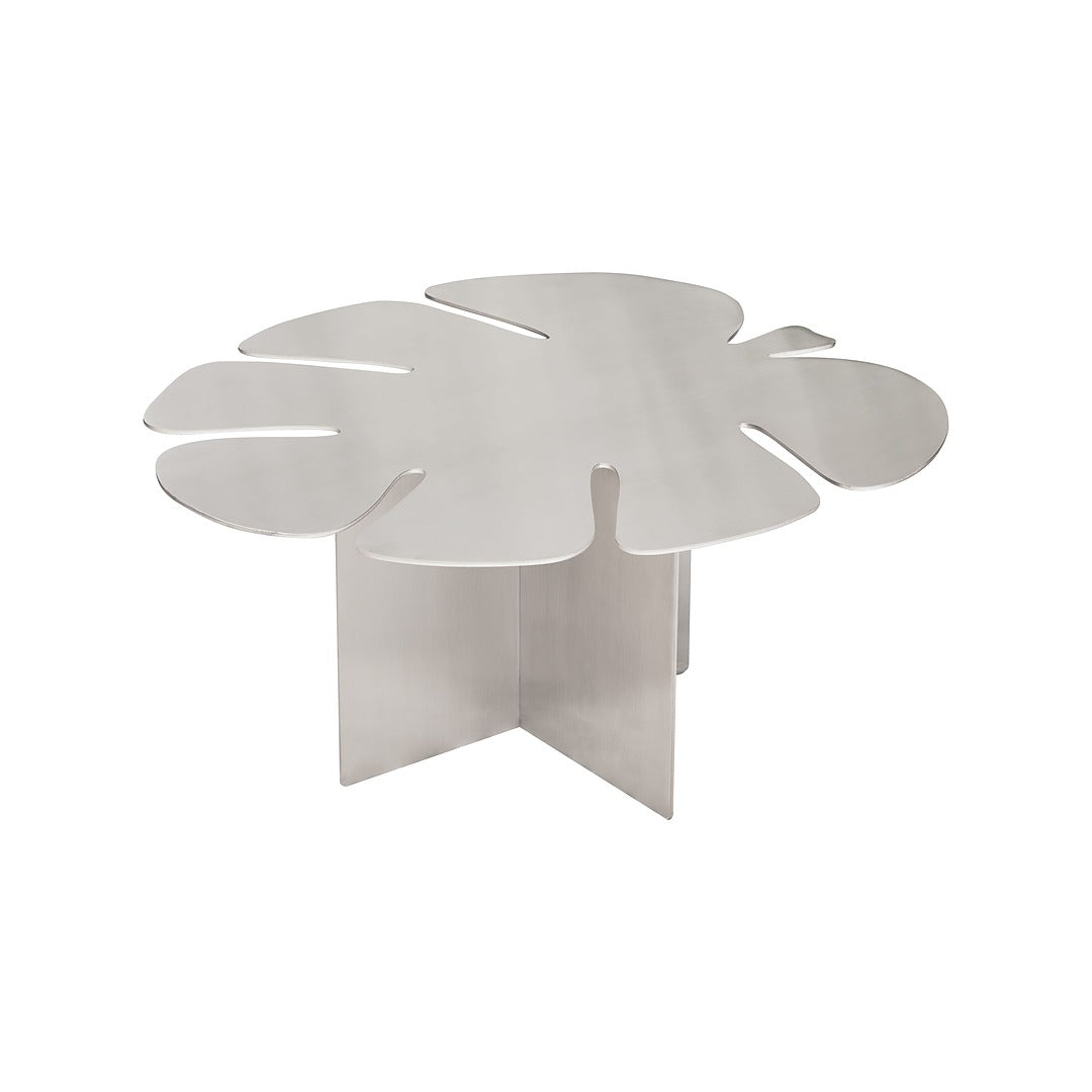Side angle view of brushed steel Monstera coffee table in clean modern interior.