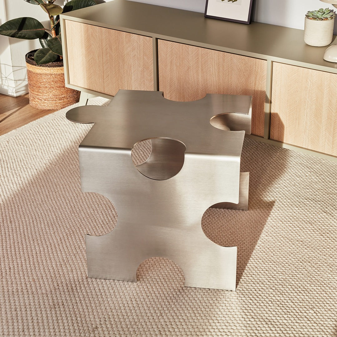Metallic side table with abstract design on a textured rug