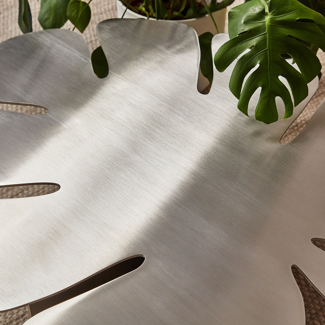 Detailed view highlighting the precise laser-cut Monstera leaf slots in brushed stainless steel.
