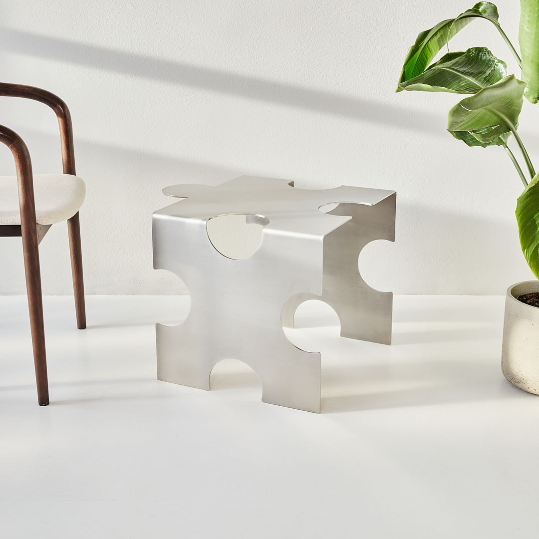 Modern side table with geometric design in a minimalistic room with a chair and plant.